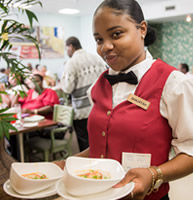 Hospitality student serves the soup with a smile